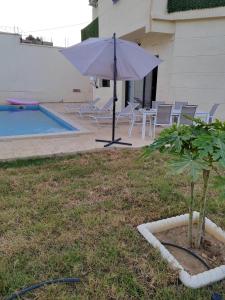 a white umbrella sitting in a yard next to a pool at Villa Lila in Cherchell
