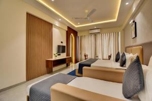 a hotel room with two beds and a couch at Hotel Sai Mahima, Near Sai Baba Temple in Shirdi