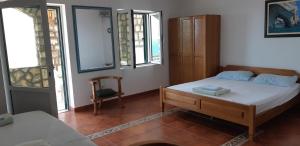 a bedroom with a bed and a chair and windows at Amore apartments in Budva