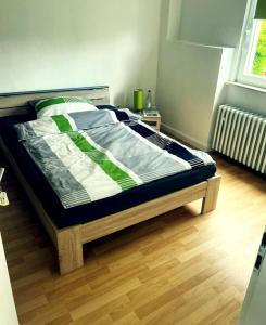 a bed in a bedroom with a wooden floor at Pension am Schottenring in Schotten