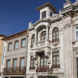 a large white building with red windows on a street at Casa em bairro típico de Aveiro in Aveiro