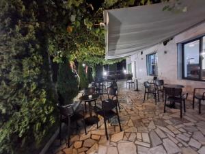 a patio with chairs and tables and a wall at Hotel Bar Restorant RRAHIMI in Shënmëri