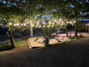a wooden bench under a string of lights under trees at Le Stéréo Motel in LʼHospitalet