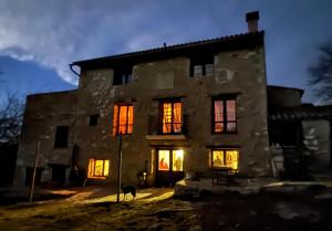 an old stone house with illuminated windows at night at Casa rural Más La Torreta con vistas al Pla de Vistabella cerca del Peñagolosa Pet Friendly niños gratis in Vistabella del Maestrazgo