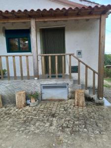 a porch of a house with a table and two logs at Casinha Meixedo in Bragança