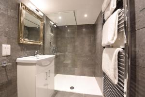 a bathroom with a sink and a toilet and a mirror at Sutherland House in Southwold
