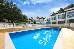 a large blue swimming pool in front of a building at Samcheok santiago pension in Samcheok
