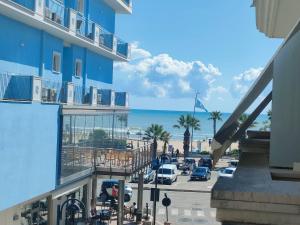 a blue building with a parking lot and the ocean at Carducci Sunrise in Tortoreto Lido