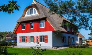 a red and white house with a thatched roof at Am Kranichland in Wieck