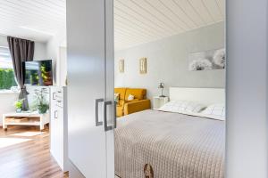 a white bedroom with a bed and a yellow chair at Sonnenblumenhaus 01 in Prerow