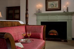 two glasses of wine on a red couch with a fireplace at Rachael's Dowry Bed and Breakfast in Baltimore