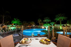 a table with food and wine glasses next to a pool at Ona Las Casitas in Playa Blanca
