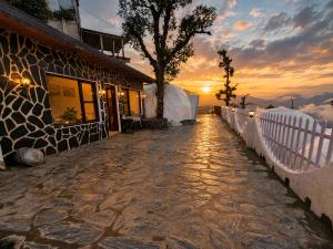 a stone walkway next to a building at sunset at The Edge Mountain Glamps & Luxury Domes Mussoorie in Mussoorie