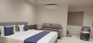 a bedroom with a large bed and a chair at Hotel Centrum in Surendranagar
