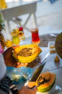 a person holding a papaya cut in half on a table at ZAN Uhuru Beach in Jambiani