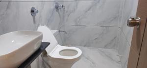 a bathroom with a white toilet and a sink at Hotel Centrum in Surendranagar