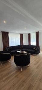 a living room with two black couches and a table at Casa Chișcău - Valea Urșilor in Chişcău