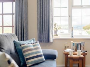 a living room with a blue couch and windows at 1 Bed in Conwy oc-79357 in Llangelynin +12 photos