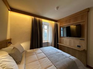 a bedroom with a large bed and a flat screen tv at Hotel Serena Cortina in Cortina dʼAmpezzo