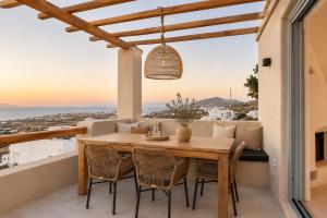 a dining room with a table and chairs on a balcony at Panthea Suite Santorini - Private pool in Vourvoúlos