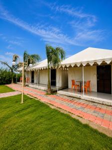 a white house with a table and chairs in a yard at Unity Sunrise Resort Statue of Unity Ekta Nagar in Kevadia