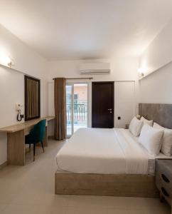 a bedroom with a large bed with a desk and a window at Hamsun Apart Hotel Clifton in Karachi