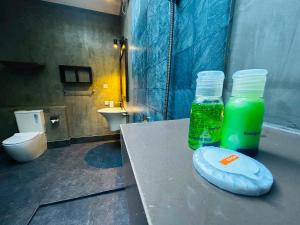 a bathroom with a toilet and two bottles of green liquid at Ela Addara Green Villa in Sigiriya