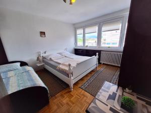 a bedroom with a white bed and a window at Apartman Pasic in Sarajevo