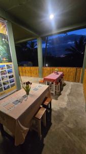 a patio with a table and benches on a deck at night at Bale Sunset Inn in Senaru