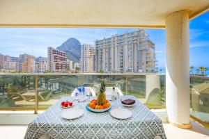 a table with a bowl of fruit on a balcony at Apartamento Larimar - PlusHolidays in Ifach