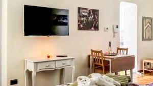 a living room with a table and a tv on the wall at Moon's House Oropa in Biella