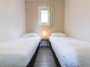 two beds in a room with a candle on a table at Park Berkenrhode in Wekerom