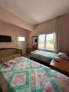 a room with two beds and a couch and a window at Yalçın Pansiyon in Silifke