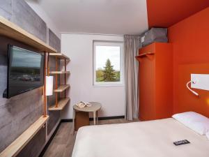 a hotel room with a bed and a tv at ibis Budget Cognac in Châteaubernard