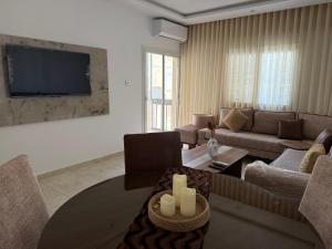 a living room with a couch and a tv at Apparemment La Perla in Banzart