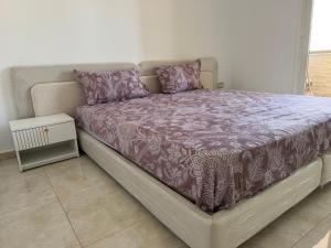 a bed with a purple comforter and pillows on it at Apparemment La Perla in Banzart