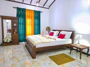 a bedroom with a bed with red pillows and a table at Dishan Green Retreat in Ambalangoda
