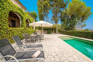 a patio with chairs and an umbrella next to a pool at Villa Calvario by Sealand Villas in Pollença