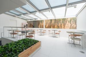 a large room with tables and chairs and plants at Connected Hotel Nonhyeon in Seoul