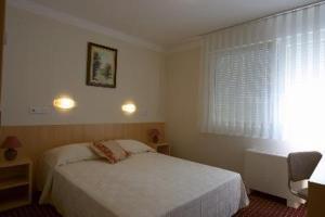 sypialnia z białym łóżkiem i oknem w obiekcie Hotel Panonija w mieście Sisak