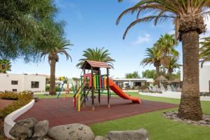 a playground with a slide in a park with palm trees at Ona Las Casitas in Playa Blanca
