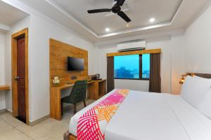a bedroom with a bed and a desk and a television at Ginger Somnath in Somnath