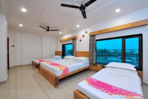 a bedroom with three beds and a large window at Ginger Somnath in Somnath +15 photos