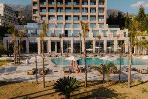 a hotel with a pool with palm trees and a building at Kaiser Resort in Dhërmi