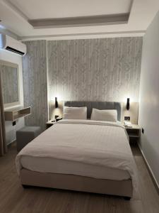 ein Schlafzimmer mit einem großen weißen Bett und einer Wand in der Unterkunft Arab Tower Hotel in Amman