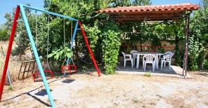 a playground with a table and chairs in a yard at Kontara Studios Anaxos in Petra