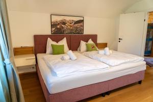 a large bed with white sheets and green pillows at Luxury Chalet with Swimming Pond Nature Escape Upper Austria in Sankt Johann am Walde +70 photos