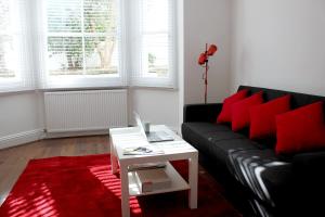 soggiorno con divano nero e cuscini rossi di West Hill Apartment a Brighton & Hove