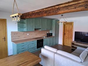 a kitchen with green cabinets and a living room at Drevenica Šumiac in Šumiac