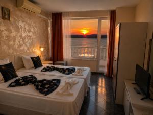 a hotel room with two beds and a window with the sunset at ORION Guest House in Sozopol